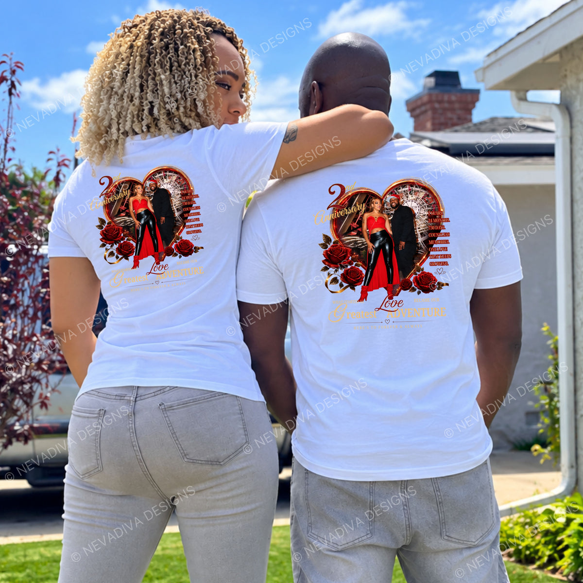 A man and a woman standing outdoors with their backs to the camera, wearing matching white graphic t-shirts featuring a red and black heart design with a couple in a red dress and roses. The background shows a suburban house, lawn, and blue sky.