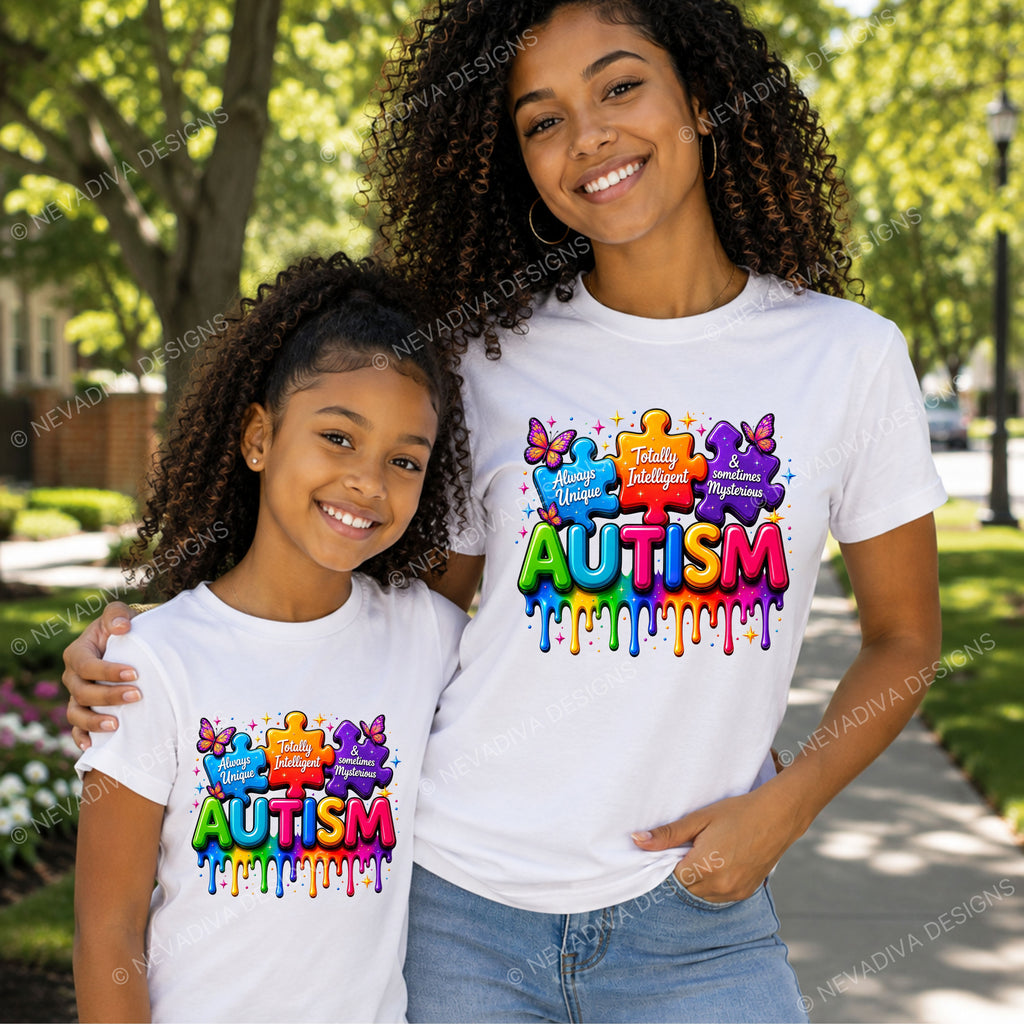 A woman and a young girl wearing matching white t-shirts with a colorful 'Autism' puzzle graphic on the front, standing outdoors on a sunny sidewalk with trees in the background.