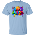 A light blue short-sleeve crewneck t-shirt featuring a colorful graphic on the chest. The graphic displays puzzle pieces and butterflies surrounding the word 'AUTISM' in dripping, rainbow-colored 3D letters, with phrases 'Always Unique', 'Really Intelligent', and 'Sometimes Mysterious' written on the puzzle pieces.