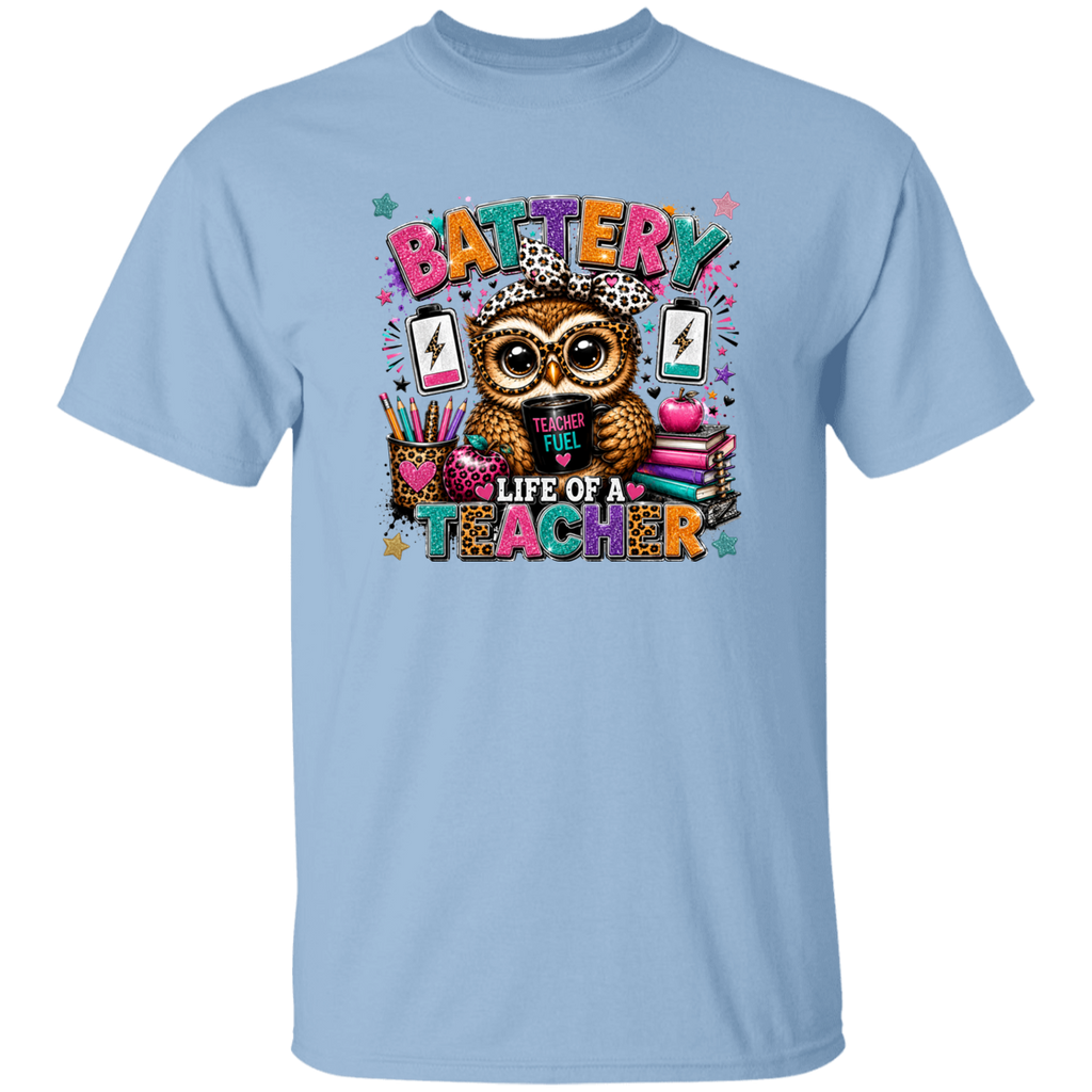 A light blue short-sleeve crewneck t-shirt featuring a colorful graphic of an owl wearing a leopard-print hat, surrounded by school supplies and the text 'BATTERY LIFE OF A TEACHER'.