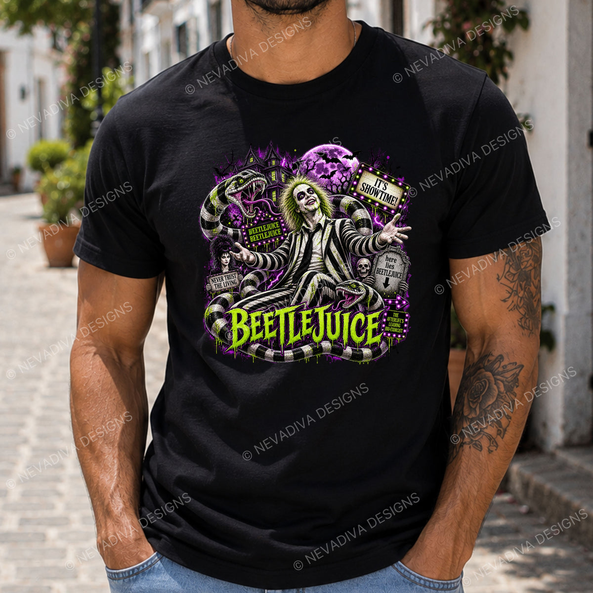 A man wearing a black graphic t-shirt featuring Beetlejuice with purple and green details, standing outdoors on a cobblestone street.