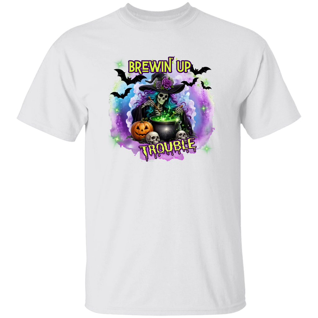 A white short-sleeve crewneck t-shirt featuring a colorful Halloween graphic on the chest. The graphic depicts a skeleton witch wearing a purple rose-studded hat and sitting by a cauldron with the text 'BREWIN' UP TROUBLE' in yellow.