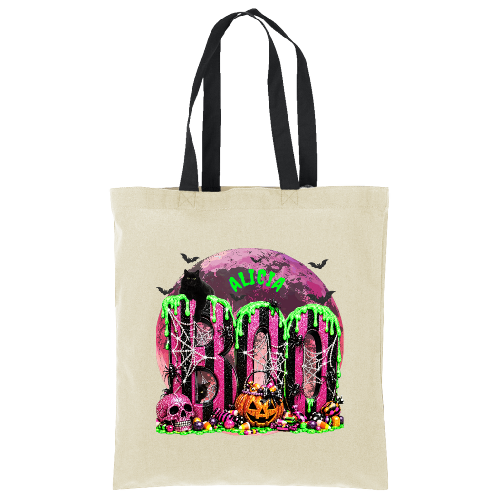 A beige canvas tote bag with black shoulder straps, featuring a colorful Halloween graphic on the front with the word 'BOO' in dripping neon green letters, a pink moon, skulls, a pumpkin, and bats.