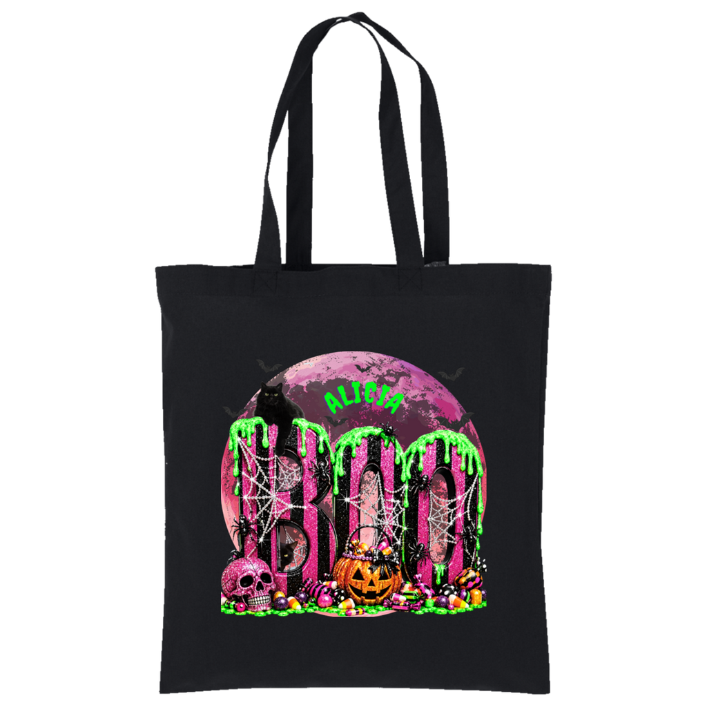 A black canvas tote bag with a vibrant Halloween graphic featuring the word 'BOO' in dripping neon green letters over a pink moon, spiderwebs, skulls, and candy, with the word 'ALIVE' in green above.