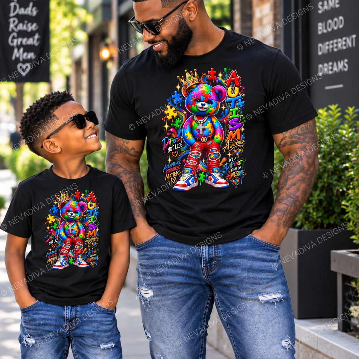A man and a boy wearing matching black graphic t-shirts with a colorful rainbow teddy bear design, standing outdoors on a city sidewalk.
