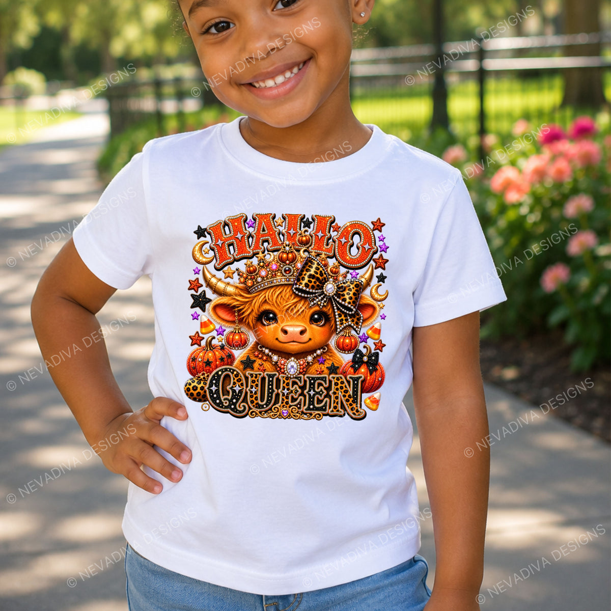 A smiling young girl wearing a white graphic t-shirt with a 'HALLO' QUEN' cow design, standing outdoors on a paved path with blurred greenery and flowers in the background.