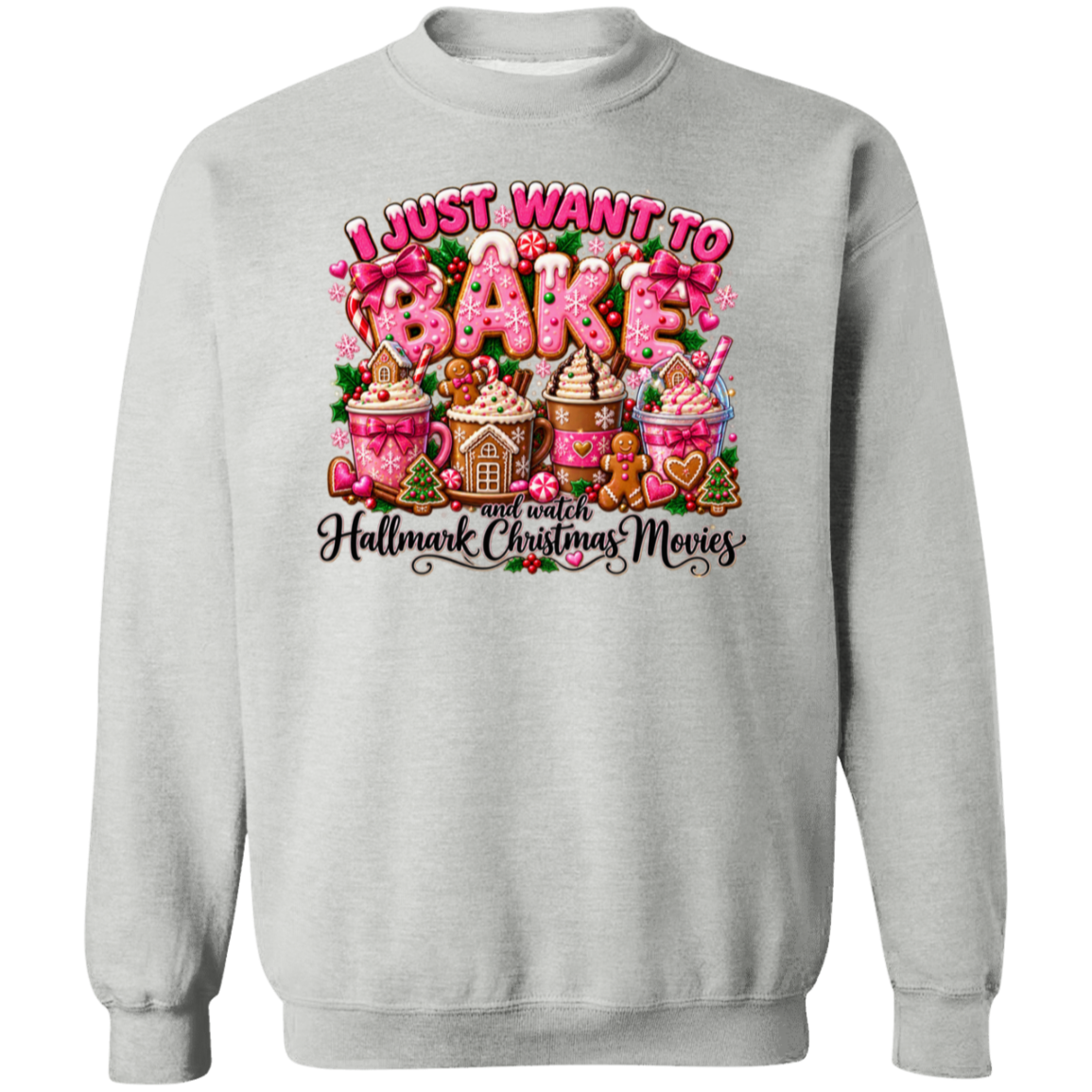 A light gray crewneck sweatshirt featuring a colorful graphic print on the front. The graphic displays the text 'I JUST WANT TO BAKE' in pink and white icing-style lettering above an illustration of hot cocoa mugs, gingerbread houses, and cookies, with the phrase 'and watch Hallmark Christmas Movies' written below in black script.