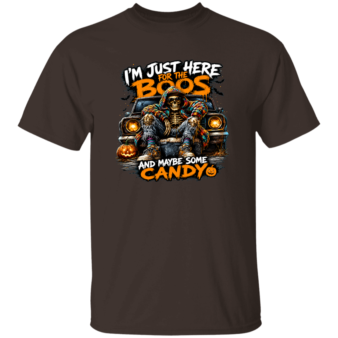 A dark brown short-sleeve crewneck t-shirt featuring a Halloween graphic of a skeleton sitting in a car with jack-o'-lanterns, accompanied by the text 'I'M JUST HERE FOR THE BOOS AND MAYBE SOME CANDY'.