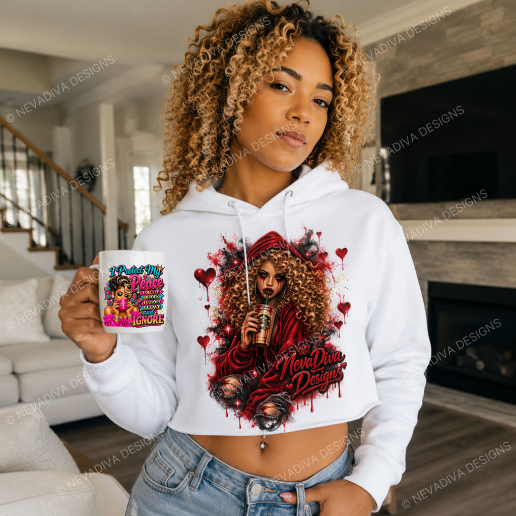 A woman wearing a white cropped hoodie with a colorful graphic print of a woman in red hoodie holding a coffee cup, standing in a living room and holding a white mug with the text 'I Protect My Peace I DELETE I BLOCK I CUTOFF I LEAVE and IGNORE'.