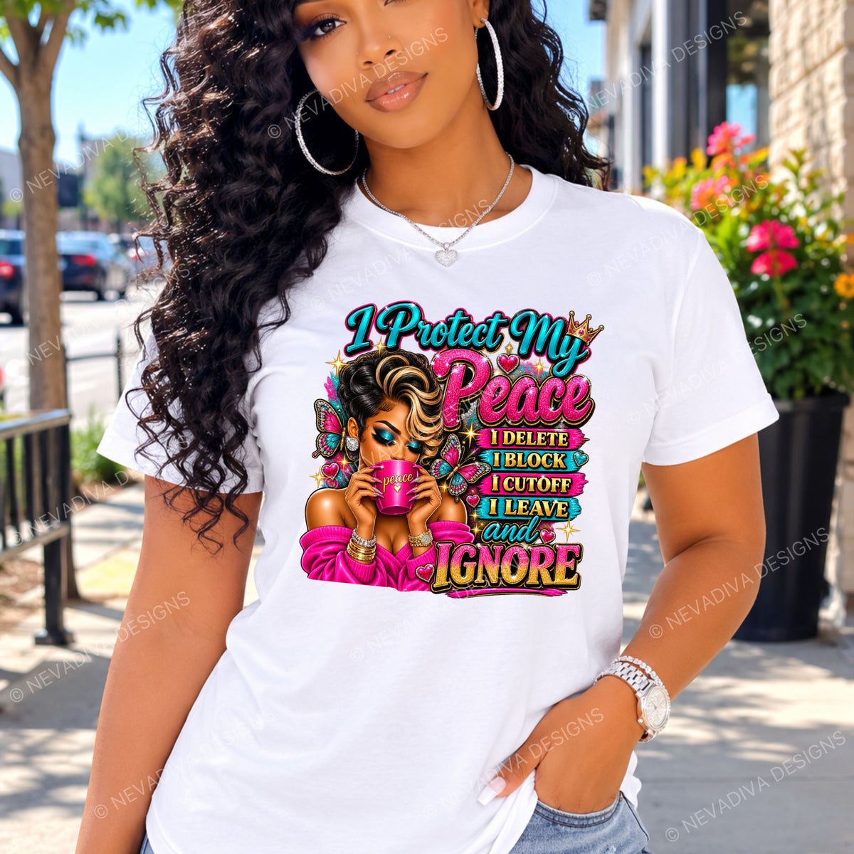 A woman wearing a white graphic t-shirt with a colorful text design that reads 'I Protect My Peace I DELETE I BLOCK I CUTOFF I IGNORE' and an illustration of a woman in pink, shown outdoors on a sunny street.