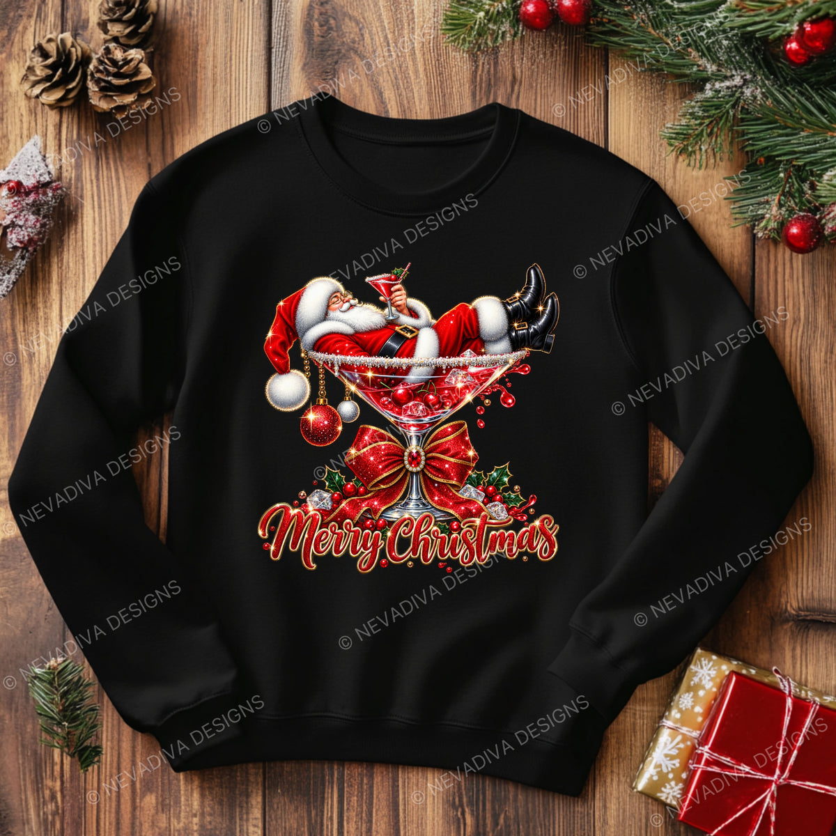 A black crewneck sweatshirt featuring a festive Christmas graphic of Santa Claus in a martini glass with 'Merry Christmas' text, displayed on a wooden background with holiday decorations.