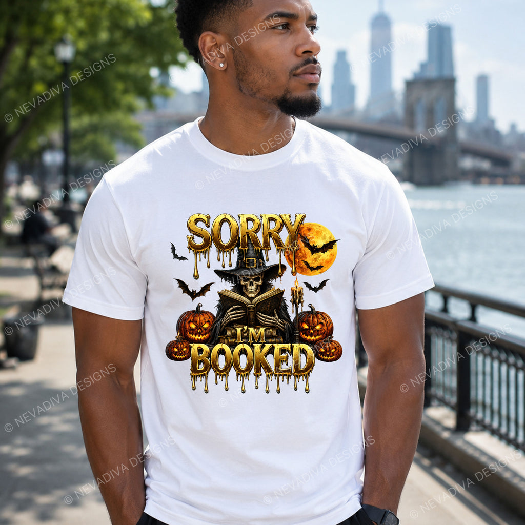 A man wearing a T-shirt with a text SORRY I'M BOOKED with a scary man next to pumpkins and bats flying