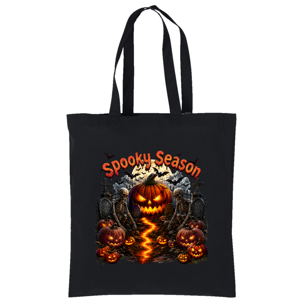 A black canvas tote bag with long black handles, featuring a colorful Halloween graphic on the front. The design includes the text 'Spooky Season' in orange, a glowing jack-o'-lantern in the center, smaller pumpkins, skeletons, tombstones, and a lightning strike effect on the ground, all set against a plain white background.