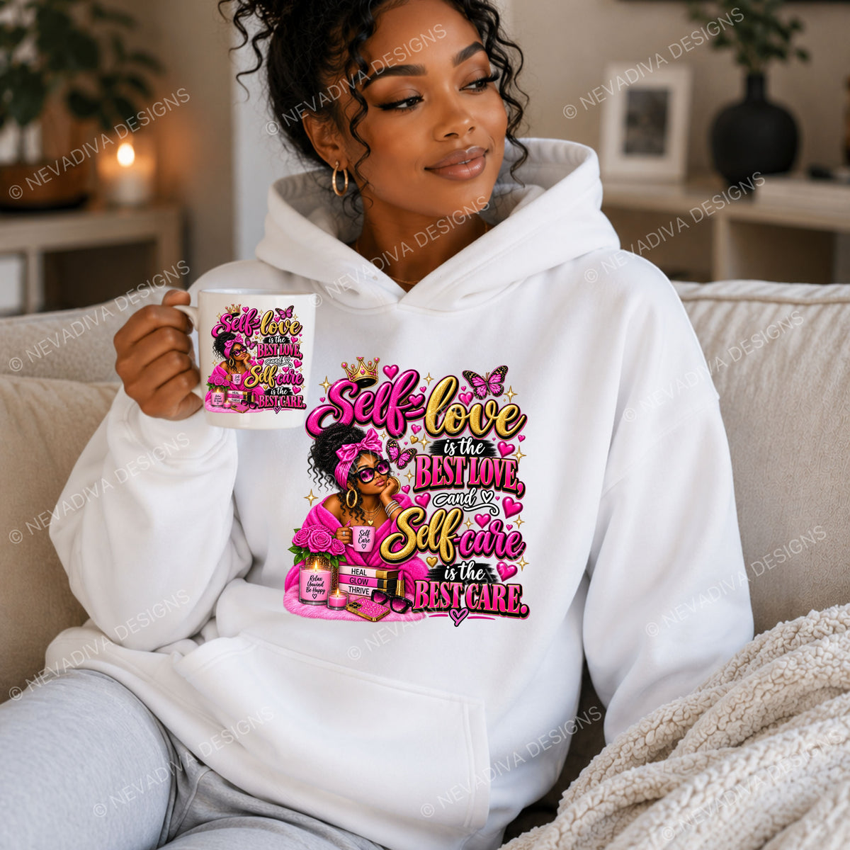 A woman sitting on a beige couch wearing a white hoodie with a colorful graphic print that reads 'Self-love is the best love and Self care is the best care' in pink, yellow, and black lettering. She is holding a matching white mug with the same design.